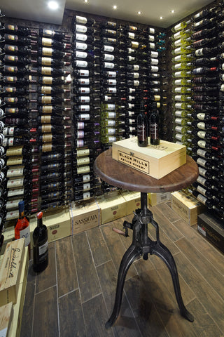 Wall mounted wine racks full of bottles cover all wall surfaces. In the centre of the room is a wooden circular table with two wine bottles on top